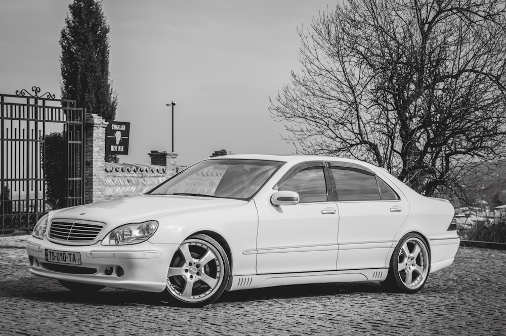 grayscale photo of sedan on road