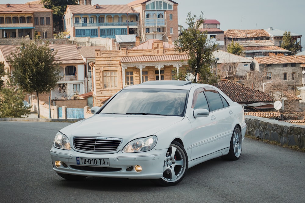 Sedán Mercedes Benz plateado estacionado al costado de la carretera durante el día