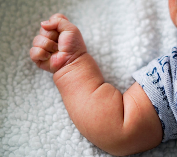 babys feet on white textile