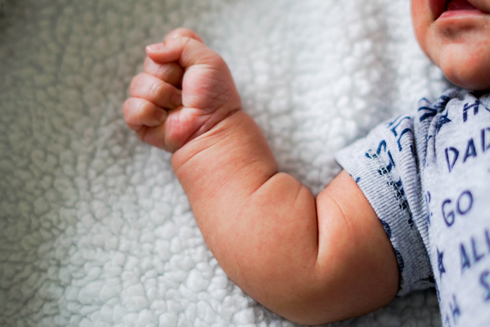 babys feet on white textile