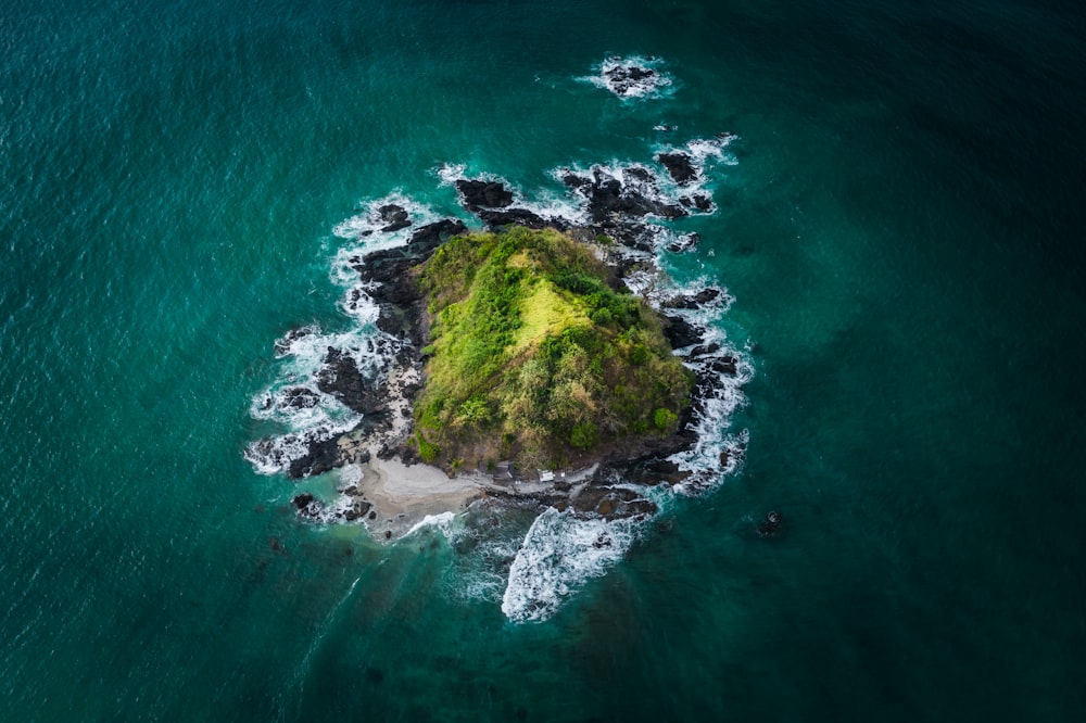 green and brown rock formation on body of water during daytime