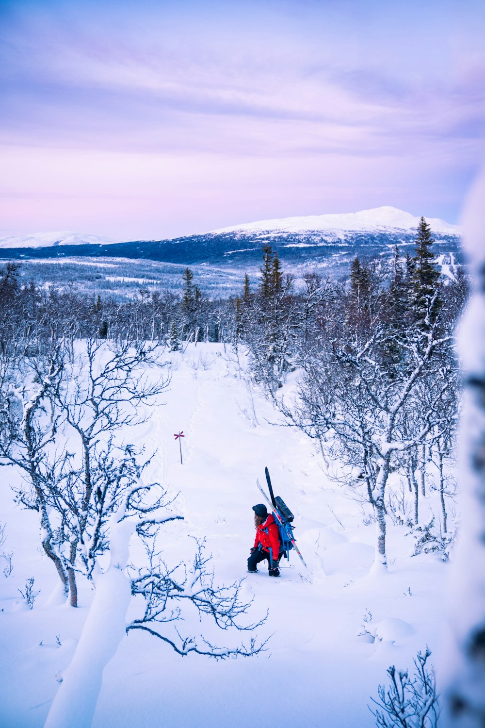 person in red jacket and black pants riding red snow sled on snow covered ground during