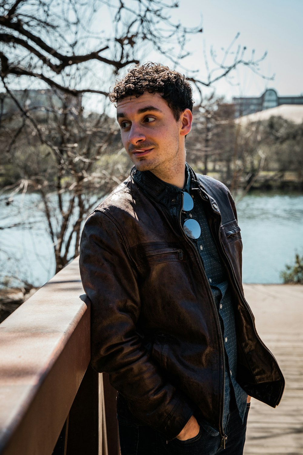 man in brown leather jacket standing near body of water during daytime