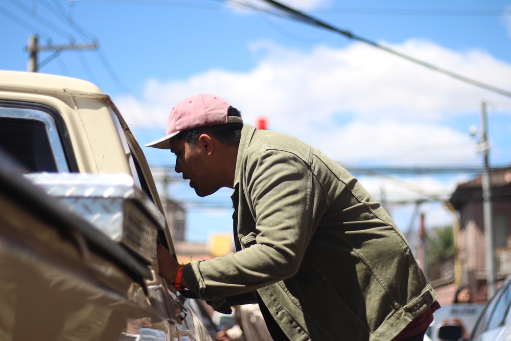 man in green jacket and red cap sitting on car