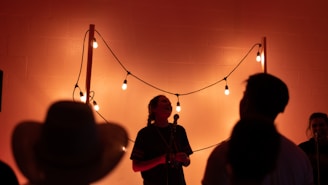 A warm, golden-lit scene of Messa Busker performing with a small, attentive audience gathered around.