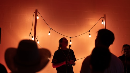 A wide shot of a small, intimate audience listening closely as kazi manam ahemed performs under warm, muted lighting.