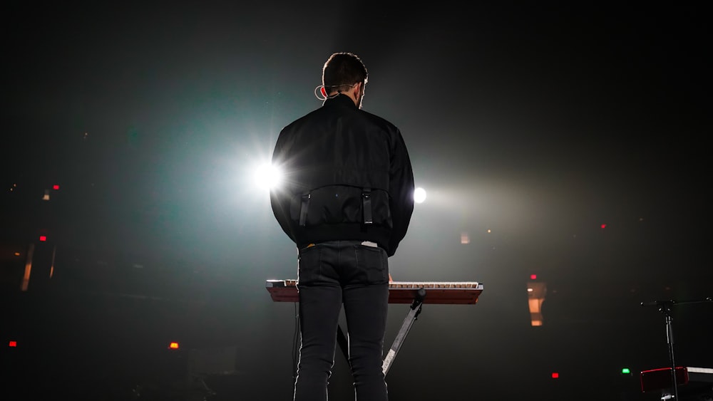 man in black leather jacket and black pants standing on brown wooden bar stool