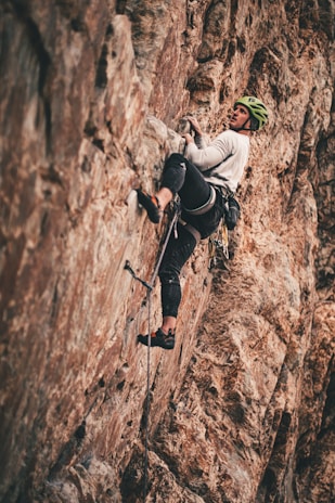 A climber rappelling down a steep rock face with focused determination.