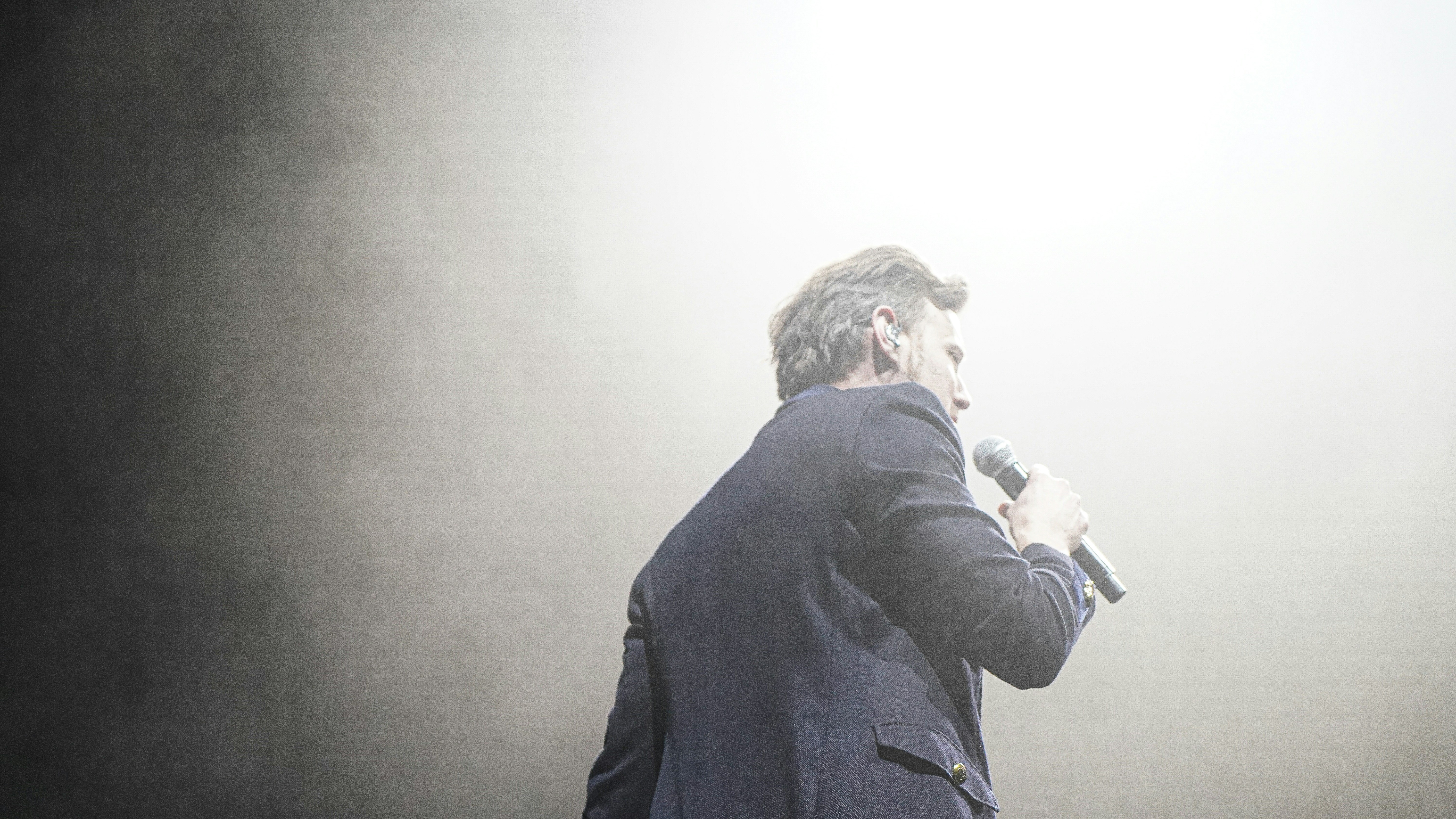 man in black suit jacket holding black dslr camera