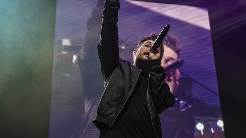 man in black jacket holding microphone
