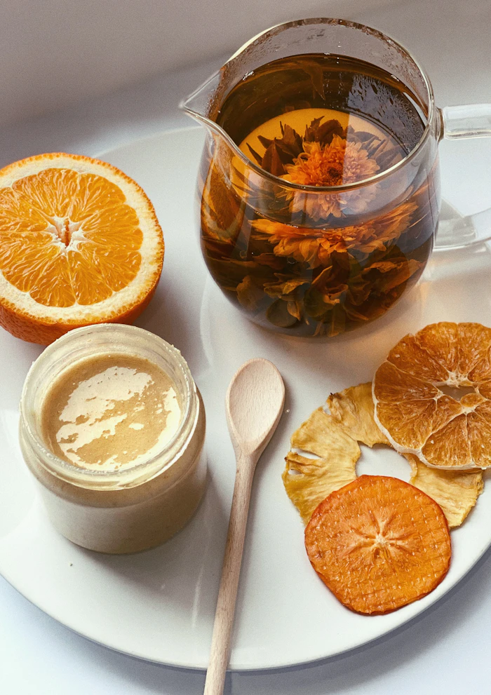 Infusion, tranches d'orange séchées et miel sur une assiette claire