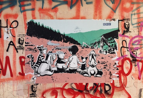 A work of street art featuring a group of cartoon animals and a child sitting on the ground, gazing toward an industrial landscape with an alien spaceship overhead. Surrounding the scene is a backdrop of graffiti with red and purple spray paint, including images of faces and abstract designs.