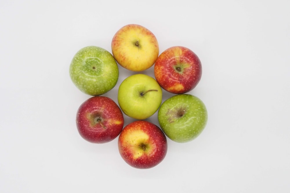 green and red apples on white surface