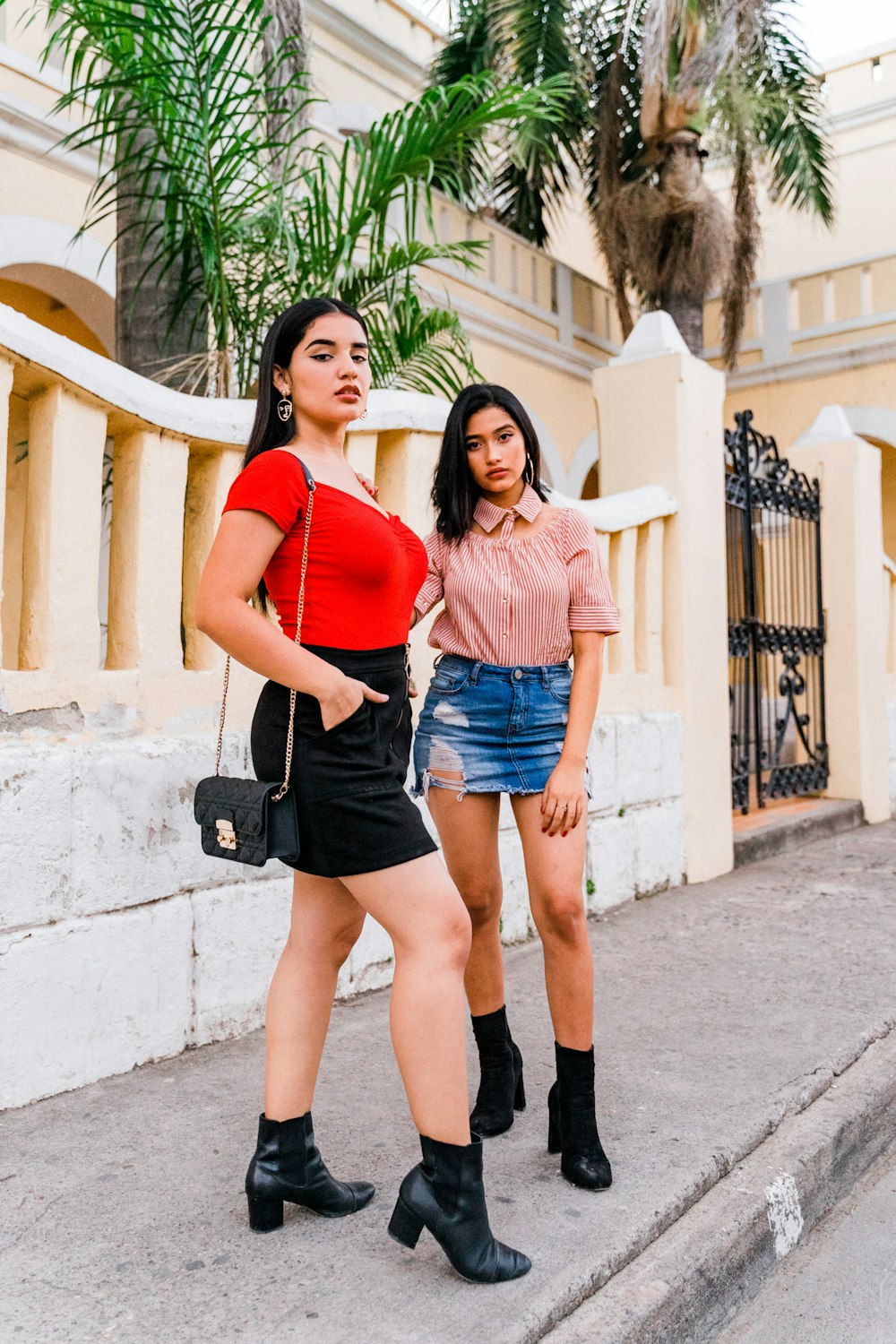 woman in red tank top and blue denim shorts standing on gray concrete floor during daytime