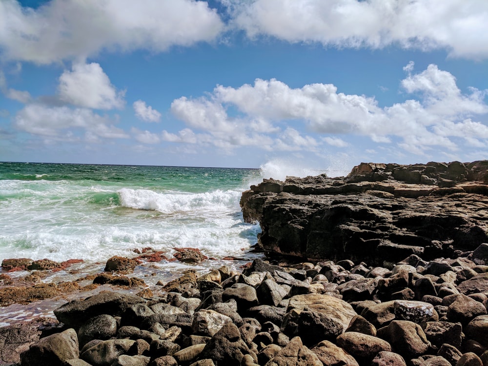 rocky shore under blue sky and white clouds during daytime