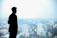 man in black suit standing on top of building looking at city buildings during daytime