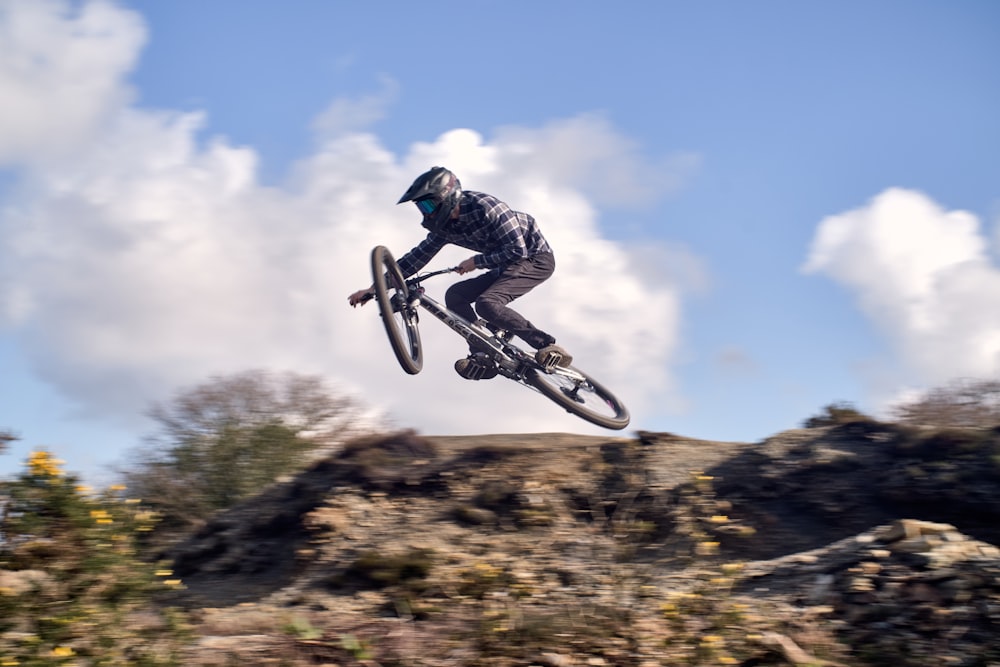 Uomo in giacca bianca e nera in sella alla bici BMX nera sotto il cielo blu durante il giorno