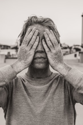 man in gray crew neck shirt covering his face with his hands
