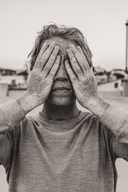 man in gray crew neck shirt covering his face with his hands
