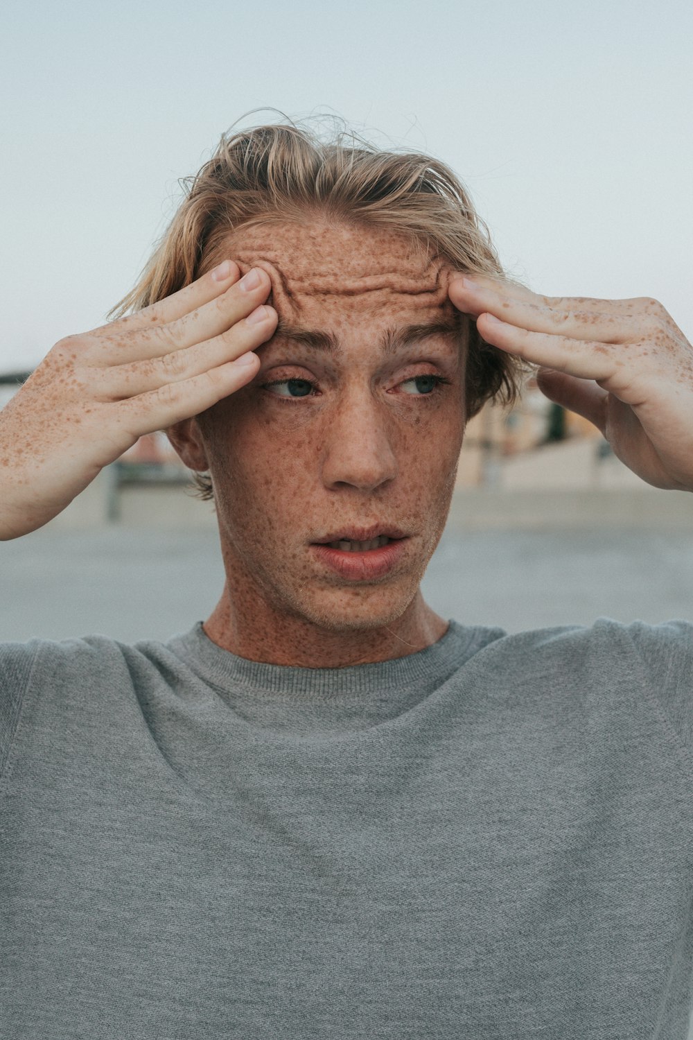 uomo in camicia girocollo grigia con capelli castani