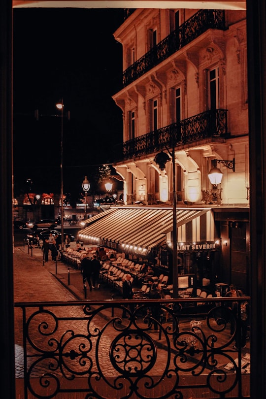 people sitting on bench near building during night time in Latin Quarter France