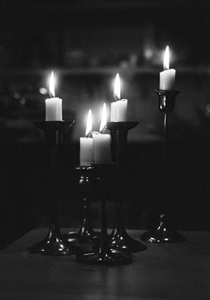Elegant black and gold candles flickering gently in a dark setting.
