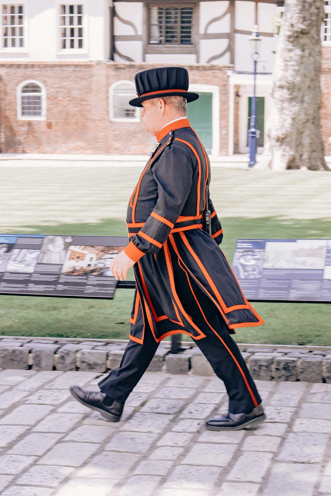 man in black and orange long sleeve dress walking on sidewalk during daytime