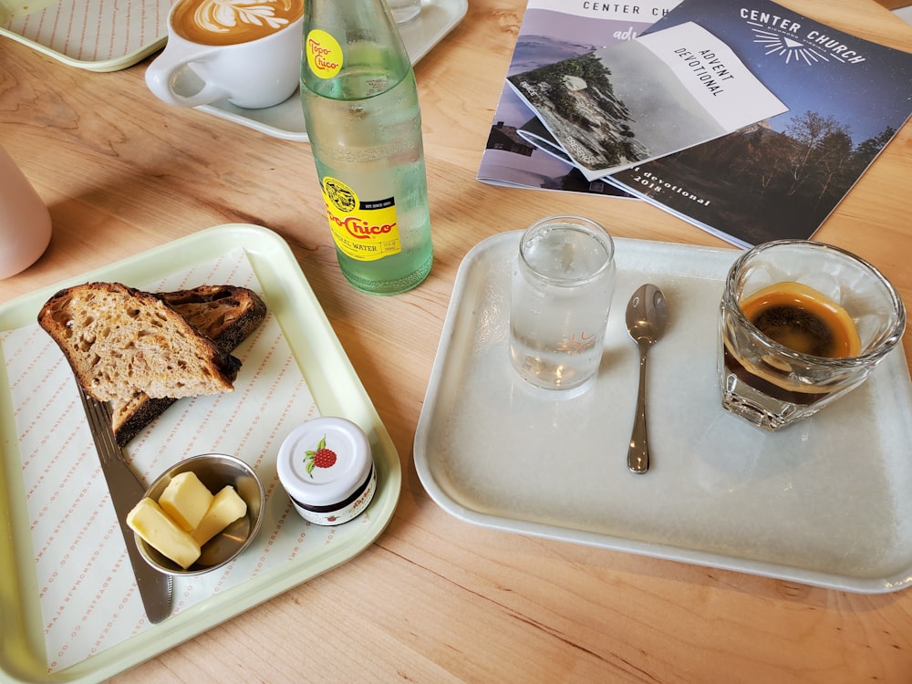 sliced apple on white ceramic plate beside clear drinking glass on brown wooden table