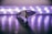 A sleek, modern knife placed on a reflective surface with a blurred background of circular lights creating a soft glow. The focus is on the detailed texture of the knife handle and its sharp blade.