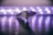 A sleek, modern knife placed on a reflective surface with a blurred background of circular lights creating a soft glow. The focus is on the detailed texture of the knife handle and its sharp blade.