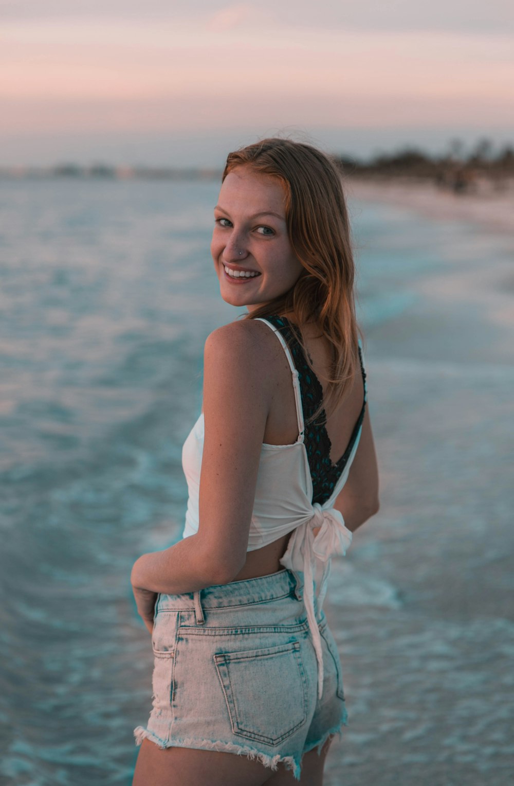 woman in black tank top and blue denim shorts standing on beach during daytime