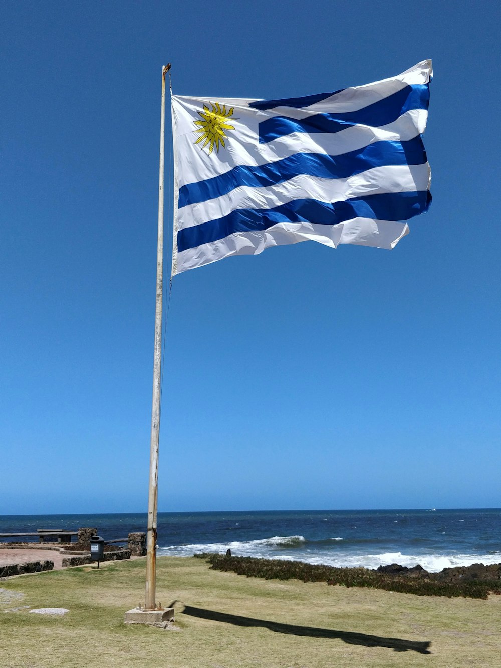 낮 동안 해변 근처 기둥에 파란색과 흰색 깃발