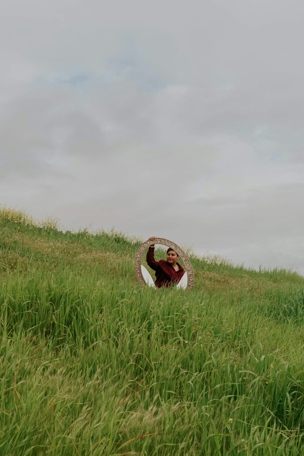 woman in brown and white hijab on green grass field under white cloudy sky during daytime