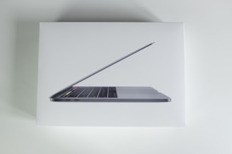 A sleek laptop with a thin design, showing part of its keyboard and the touch bar on a white background.