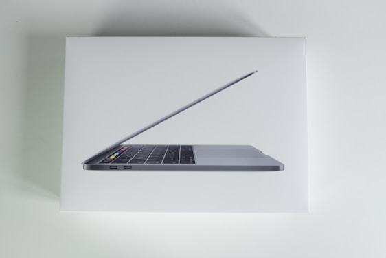 A sleek laptop with a thin design, showing part of its keyboard and the touch bar on a white background.
