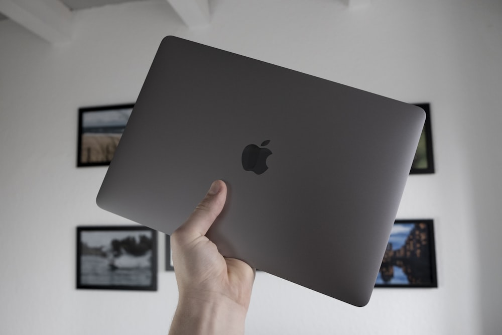 silver macbook on persons hand