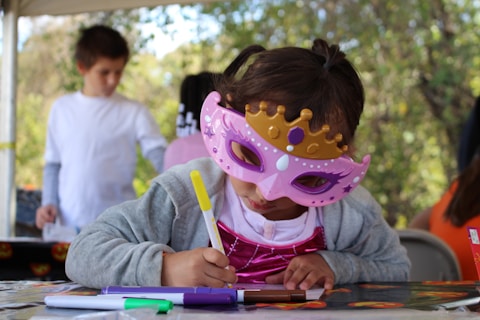 girl in gray sweater with pink and white mask