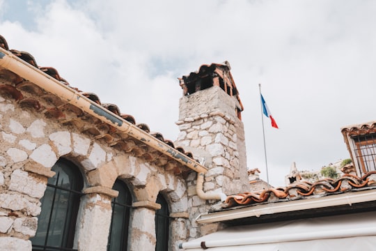 brown brick building with flags on roof under blue sky during daytime in Provence France