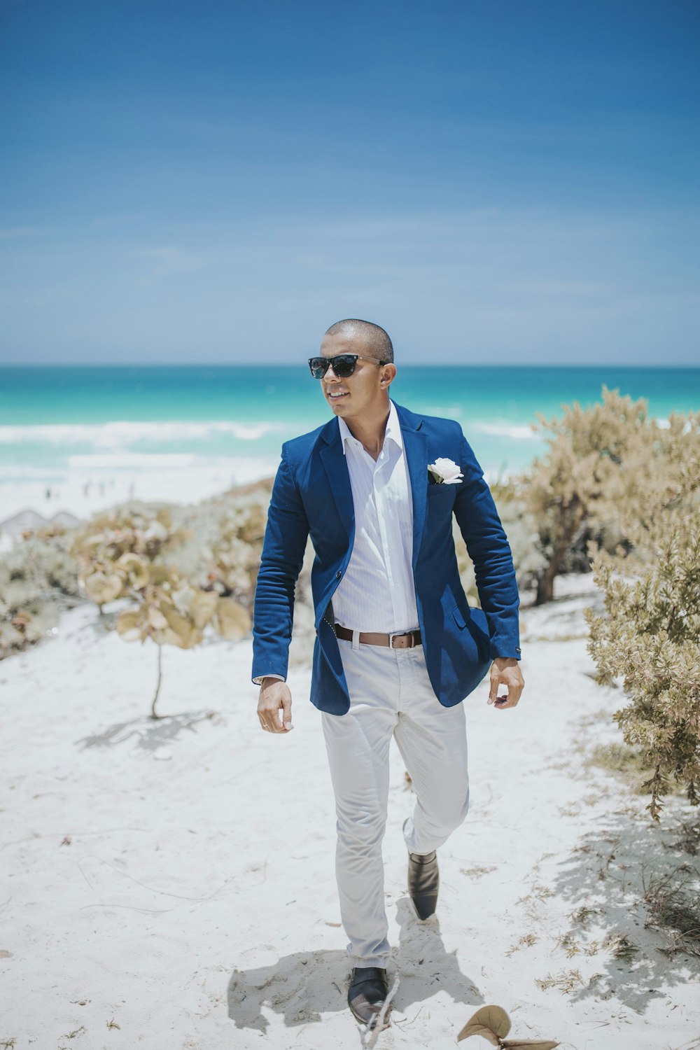 man in blue suit standing on white sand near body of water during daytime