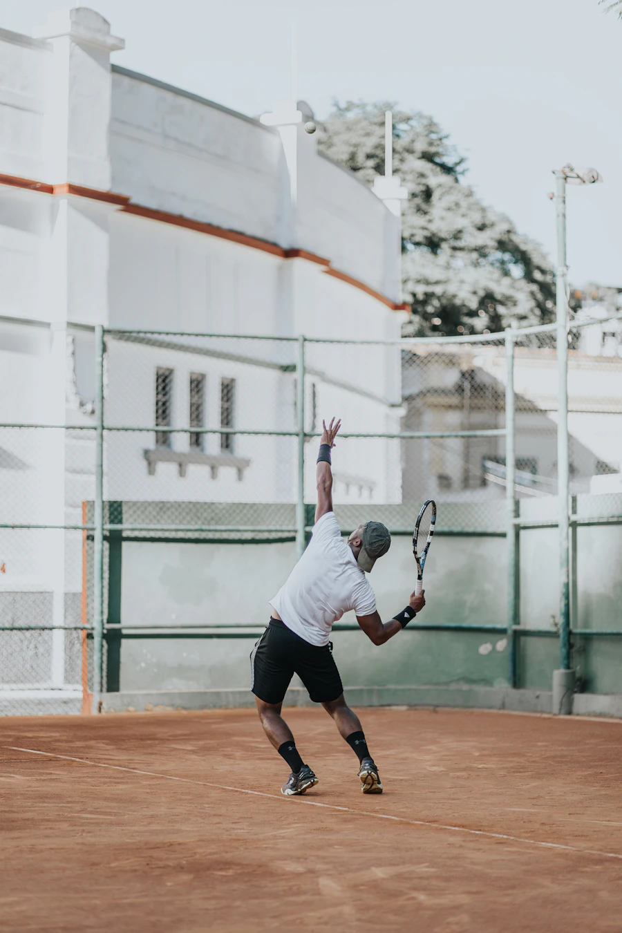 Saque de competición — jugador lanzando la bola en una pista de tierra batida