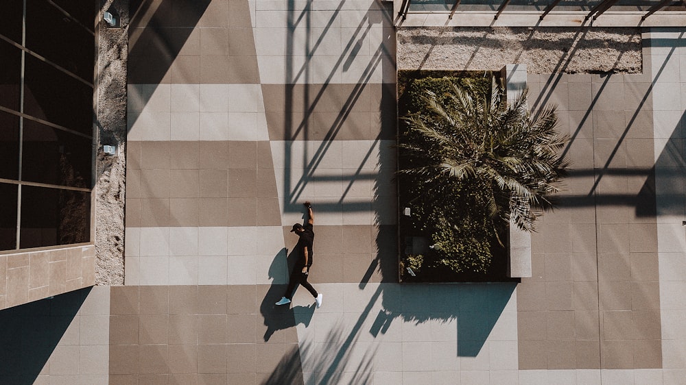 man in black jacket and black pants jumping on blue and white concrete wall during daytime