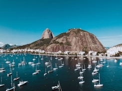 boats on sea near brown mountain under blue sky during daytime