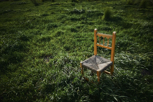 A beautifully crafted rattan chair placed in a serene outdoor setting.