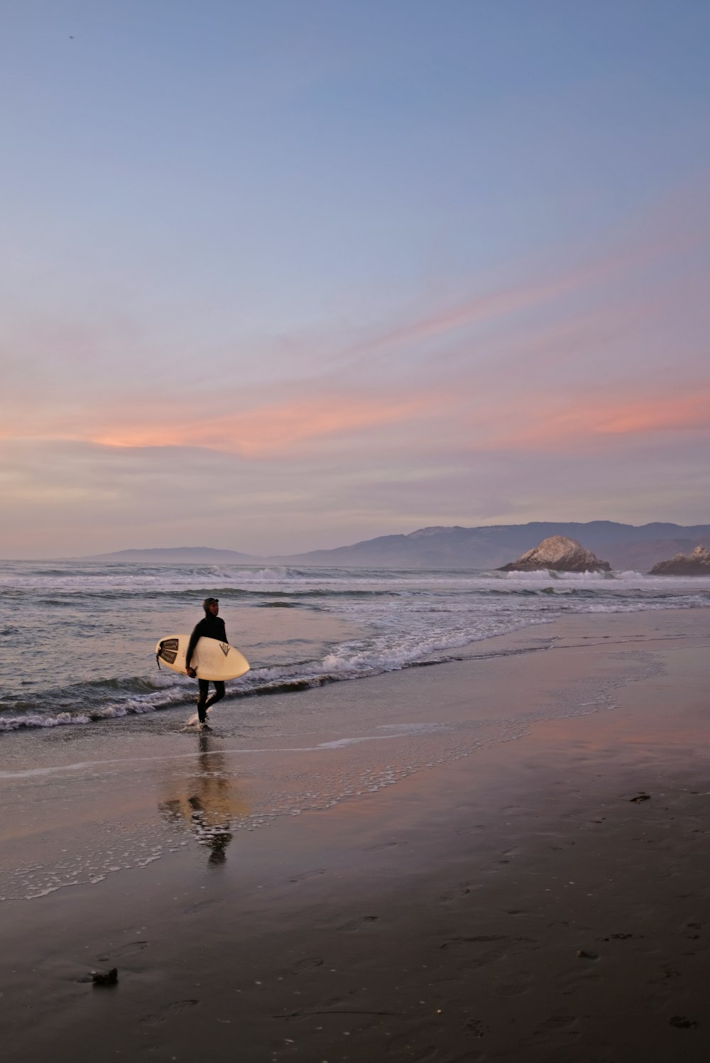 woman in black dress walking on beach during sunset