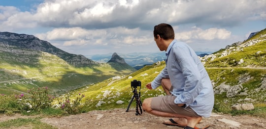 man in gray long sleeve shirt sitting on brown rock during daytime in Durmitor Montenegro