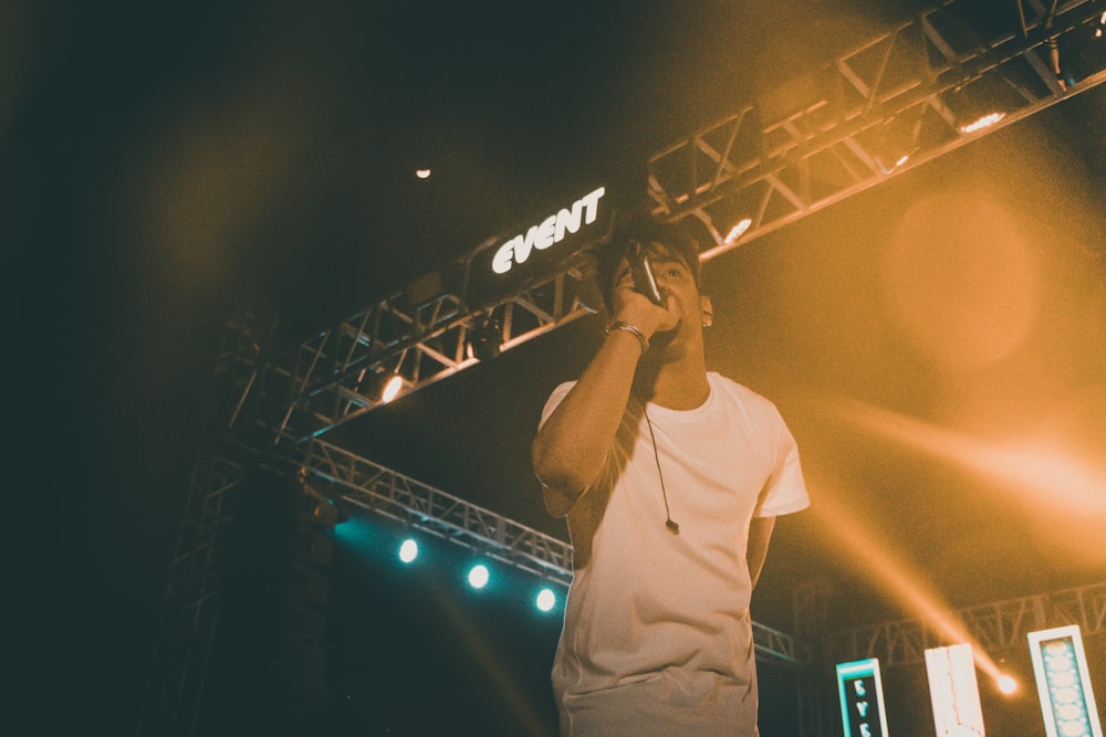 man in white long sleeve shirt singing on stage