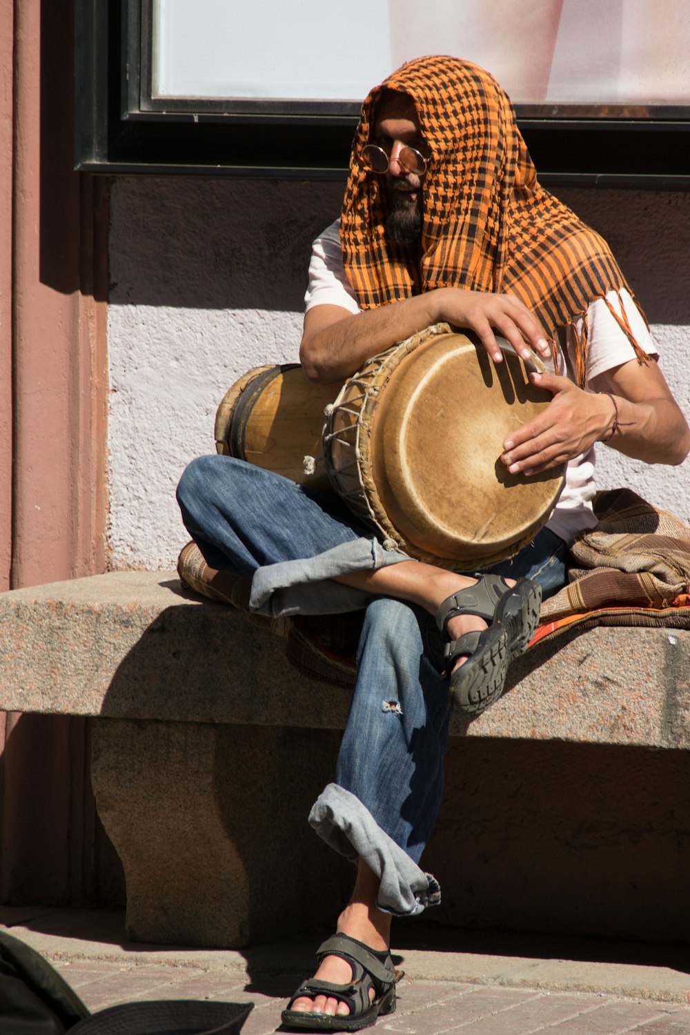 person in blue denim jeans sitting on brown concrete bench