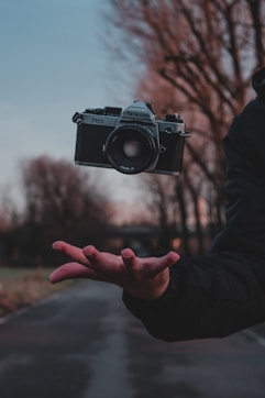 person holding black and silver camera