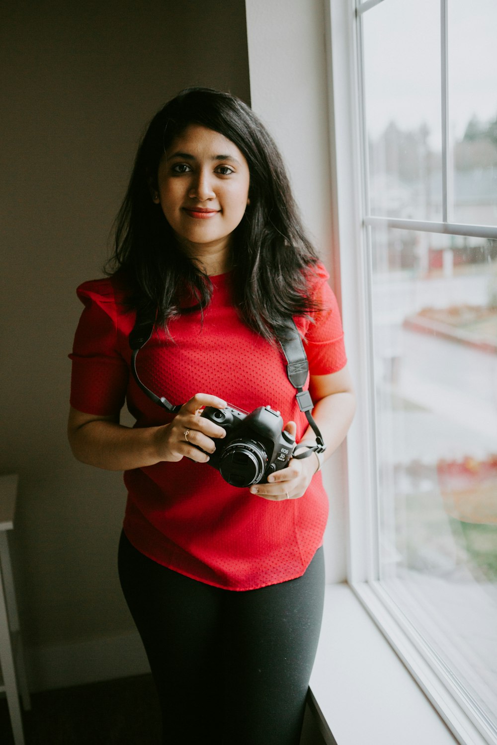 woman in red long sleeve shirt holding black dslr camera