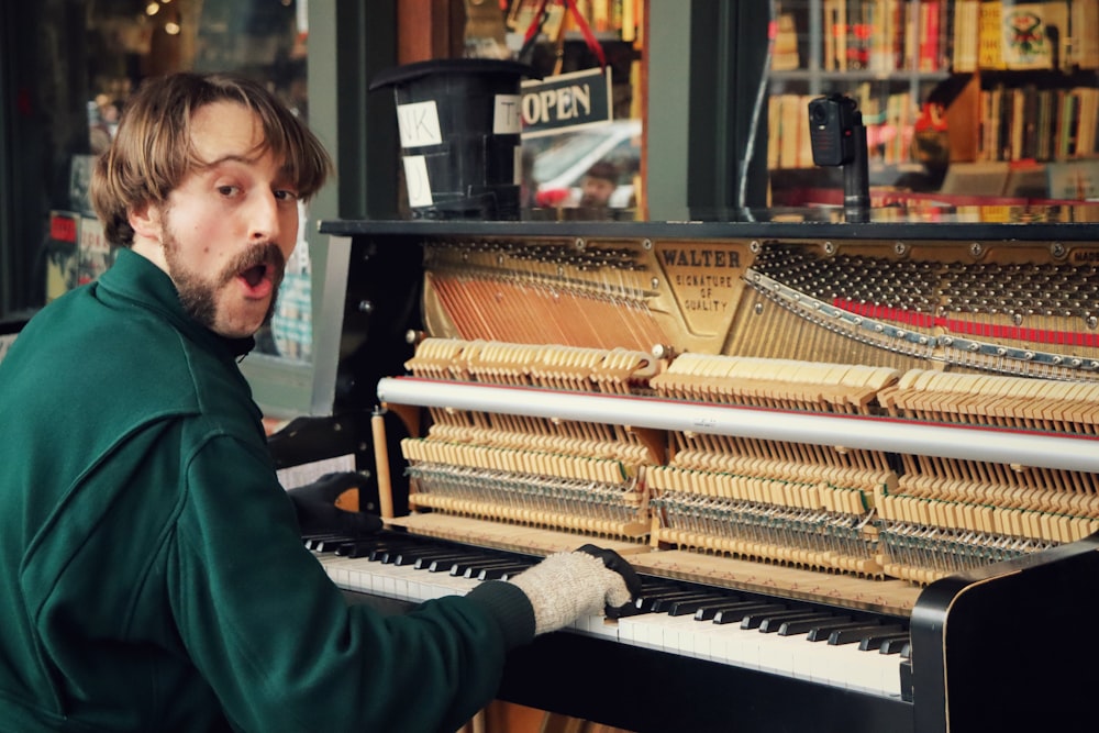 man in green sweater playing piano